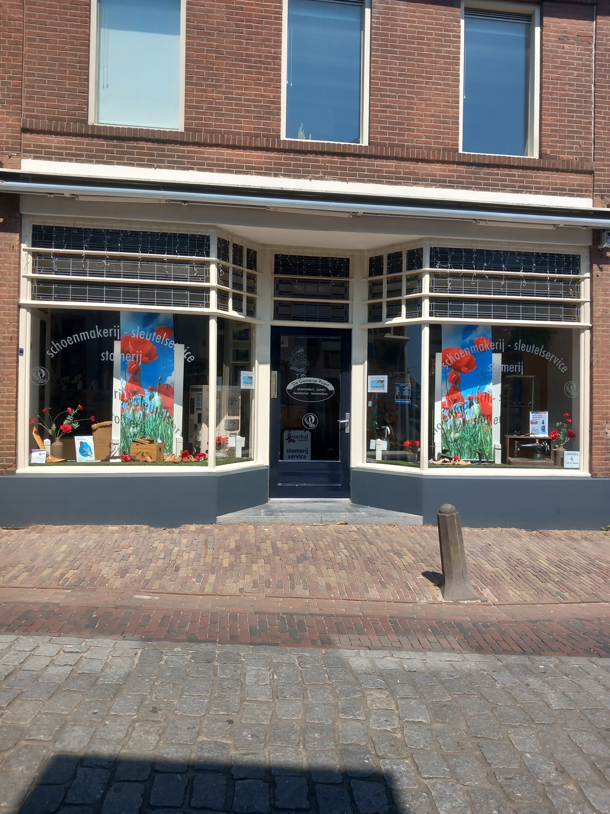 De winkelpui van voren, met klaprozen op de banieren in de etalage